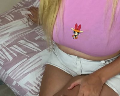 A slut wearing a pink shirt with cartoons on it sits on a bed.