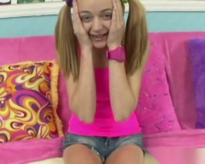 Pink girl wearing pigtails and shorts sitting on pillows