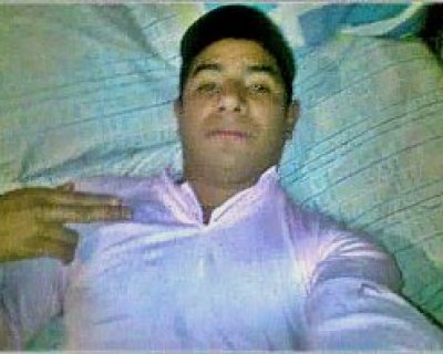 Young male lying down on bed making offensive hand gesture