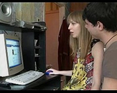 A girl is typing on a white computer with a guy looking on.