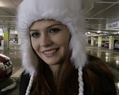 Smart blonde girl wearing winter hat smiles at camera