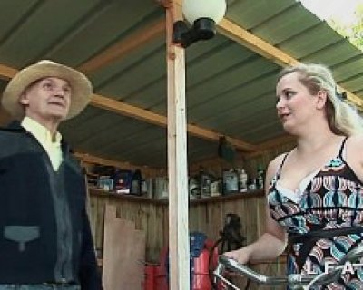 An old man talking to a young whore outside of a shed.