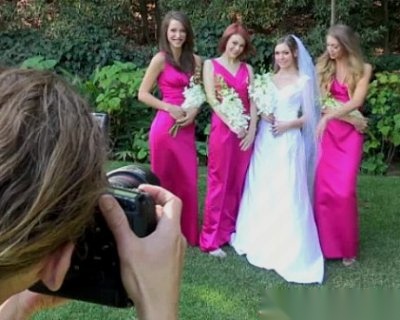 Bridesmaids wearing pink dresses and holding white flowers pose for a picture.