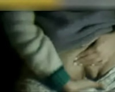 The person is lying on a bed in a dark room.