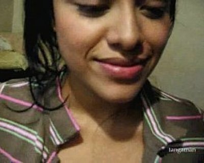 A lady in a brown top with her eyes closed.