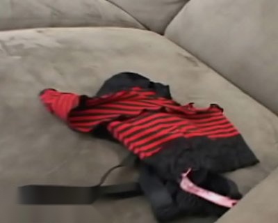 A strappy red and black thong is on a sofa.