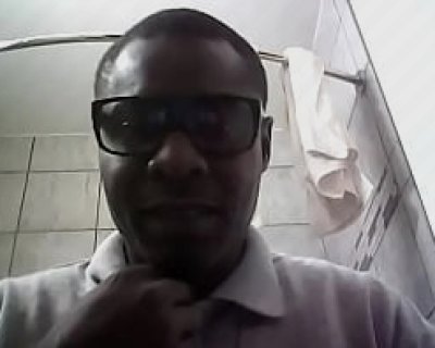 A man wearing glasses and white shirt sitting on toilet with his mouth open