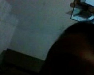 A hairy face peeks around the corner of a mirror in a dark room.