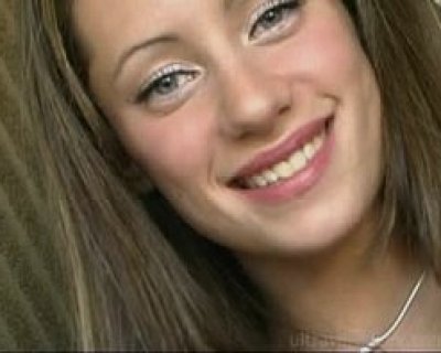 She is smiling and has a necklace on.