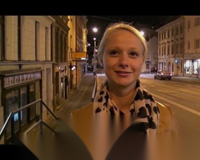 A bimbo smiles for the camera. The background is dark.