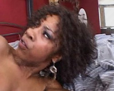 A young slut is laying in bed wearing a black shirt and earrings.