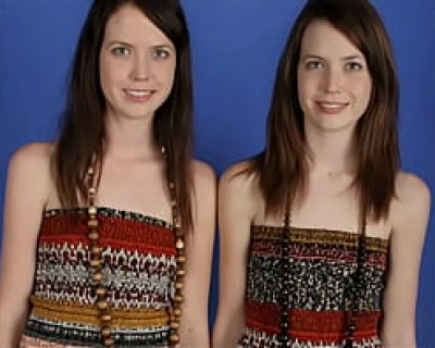 Identical twin girls wearing beads &amp; chains pose for camera.