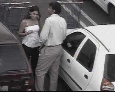 A slut talks on a cell phone. The man behind her is smoking the cigarette.
