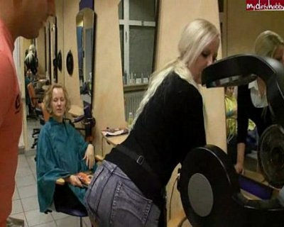 Blonde bimbo in black dress blow drying her hair.