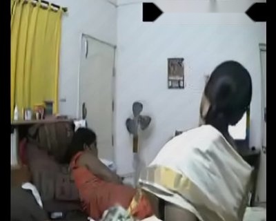 Two women sit in chairs and watch a TV.