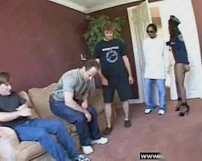 A fucker is sitting on a couch. Other people are standing.
