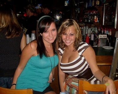 Two women sitting at the bar. They are smiling and posing for a picture.