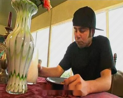 A boy sitting at table holding bowl and vase.